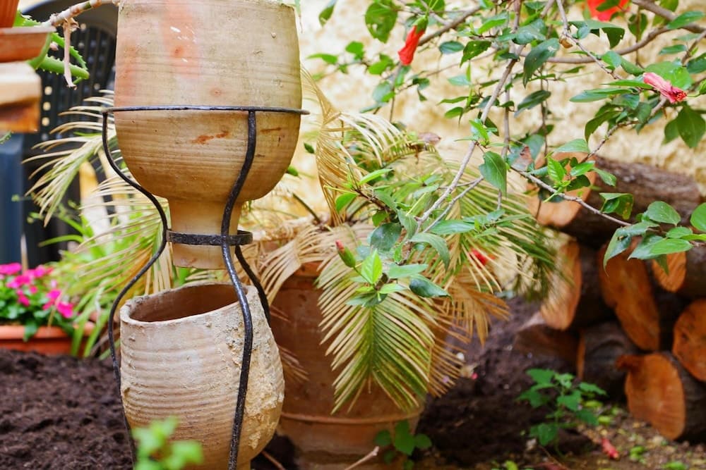 A serene garden scene features terracotta pots, vibrant flowers, and lush greenery, ideal for travelers seeking peaceful outdoor relaxation spaces.