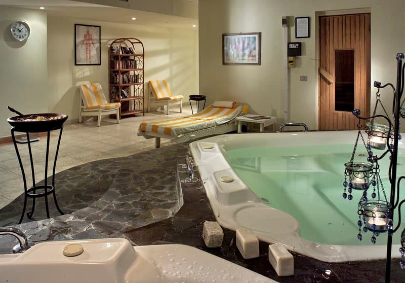 A serene indoor spa area features a hot tub, lounge chairs, and decorative candles, ideal for relaxation and wellness retreats.