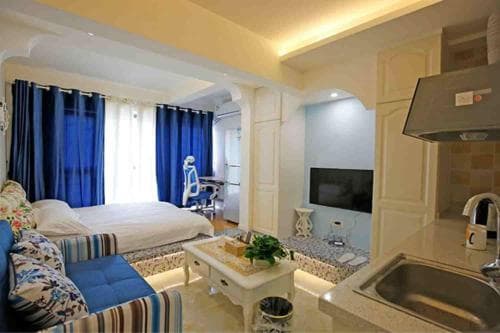 A cozy studio apartment featuring a vibrant blue-themed living space, a compact kitchenette, and a serene bedroom area, ideal for travelers seeking a comfortable and stylish short-term stay.