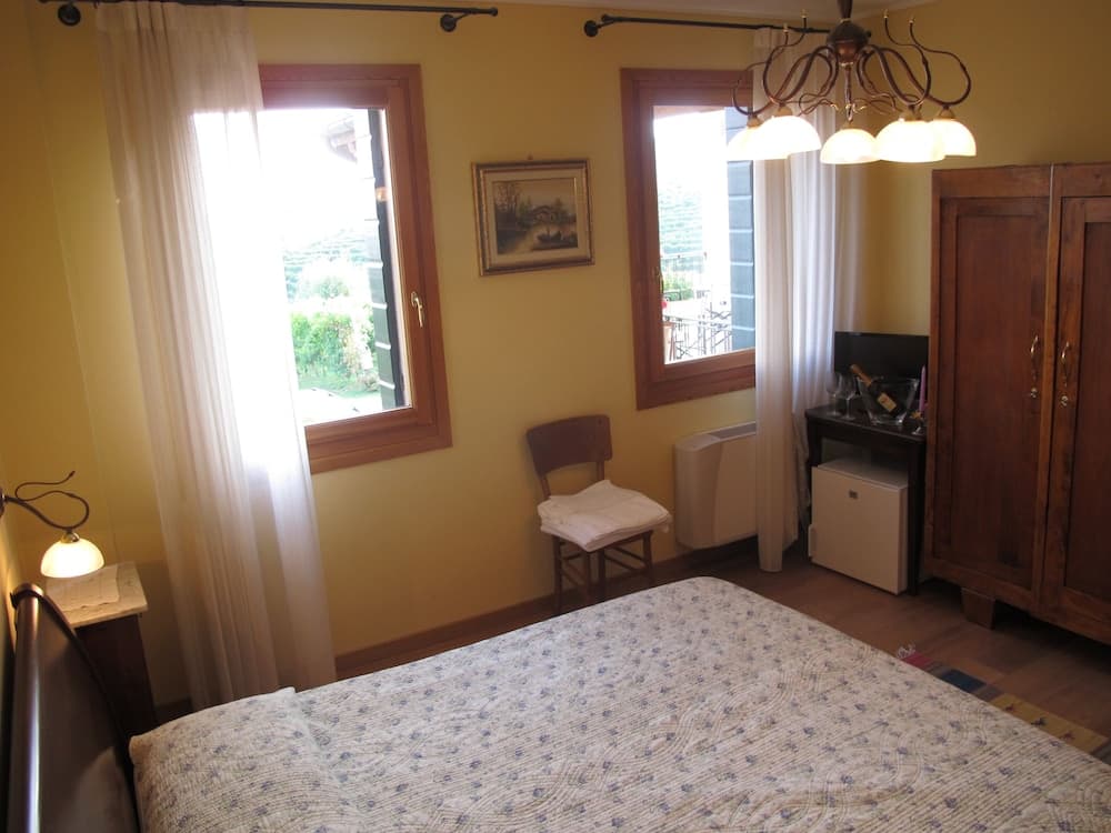 A cozy bedroom with yellow walls, wooden furniture, and large windows offering a serene view, ideal for travelers seeking a peaceful retreat.