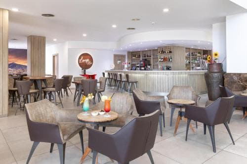 A cozy hotel lounge features modern seating, a well-stocked bar, and warm lighting, creating an inviting atmosphere ideal for travelers seeking relaxation or casual meetings.