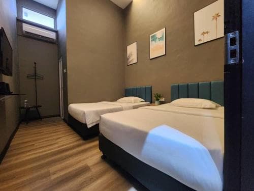 A cozy hotel room with two neatly made beds, modern decor, and wooden flooring offers a comfortable stay for travelers seeking a serene and stylish retreat.