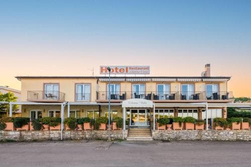 A charming hotel with a welcoming facade, outdoor seating, and lush potted plants exudes a cozy and inviting atmosphere, perfect for travelers seeking relaxation in a picturesque setting.