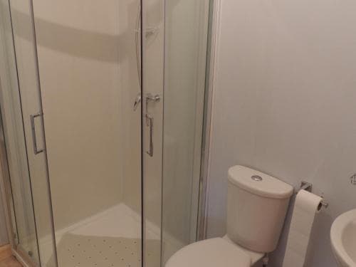 A clean, minimalist bathroom featuring a glass-enclosed shower, white toilet, and sink, ideal for travelers seeking compact and functional accommodations.