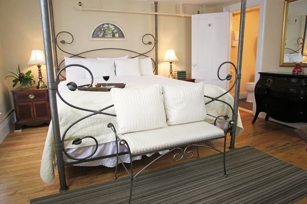 A cozy bedroom with a four-poster bed, soft lighting, and elegant furnishings creates an inviting atmosphere ideal for a romantic getaway.