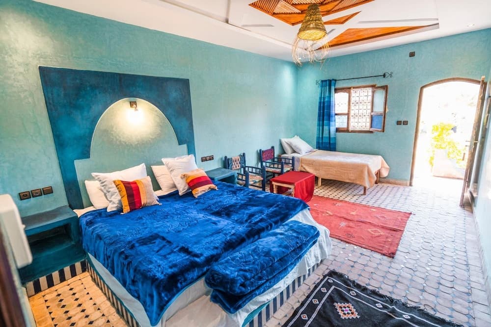 A serene Moroccan-style bedroom with turquoise walls, patterned rugs, and a cozy bed setup invites travelers seeking a tranquil and culturally rich accommodation experience.