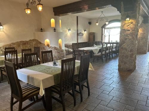 A cozy indoor restaurant with rustic stone pillars, warm lighting, and neatly arranged tables invites travelers to enjoy a relaxing dining experience.