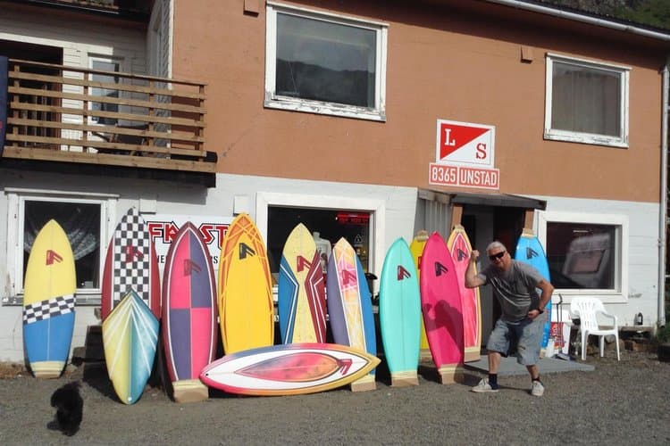A vibrant surf shop in Norway displays colorful boards against an orange building, inviting travelers to explore the adventurous spirit of Lofoten's coastal culture.