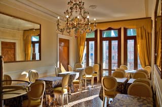 An elegant dining room with ornate chandeliers, golden curtains, and classic furniture exudes sophistication, ideal for travelers seeking a luxurious restaurant experience.