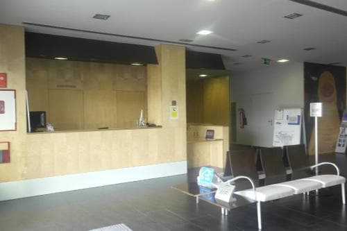 A modern, minimalistic airport lounge features sleek wooden counters, comfortable seating, and a calm atmosphere, ideal for travelers seeking a quiet waiting area before their flight.