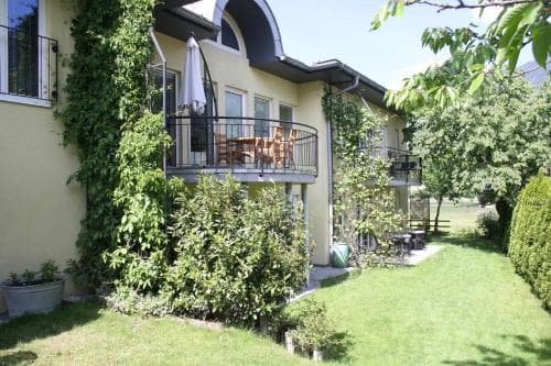 A serene garden villa with lush greenery, a cozy balcony setup, and inviting outdoor seating offers a tranquil retreat ideal for family vacations or romantic getaways.