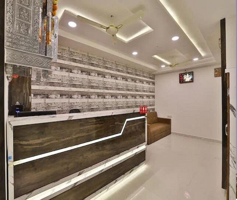 A modern hotel lobby features a sleek reception desk with illuminated wood paneling, a textured stone wall backdrop, and cozy seating, creating a welcoming atmosphere ideal for travelers seeking comfort and style.