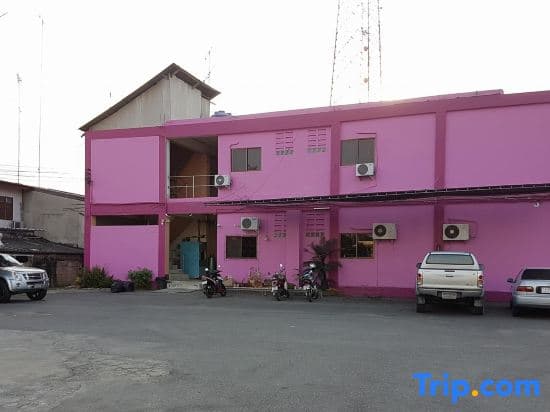 A vibrant pink building with motorcycles parked outside exudes a quirky charm in an urban setting, ideal for travelers seeking unique accommodations or photo opportunities.