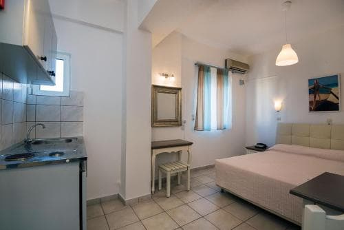 A cozy studio apartment features a compact kitchenette, a neatly made bed, and soft lighting, creating an inviting atmosphere ideal for travelers seeking comfort in a small, functional space.