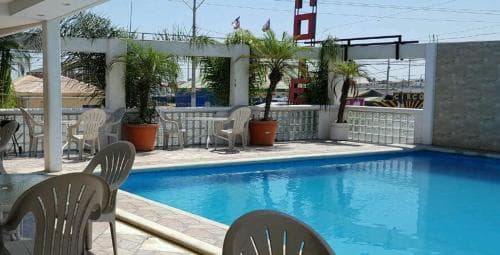 A sunny outdoor poolside area with lounge chairs, potted plants, and a festive atmosphere offers a relaxing retreat for travelers seeking leisure and recreation.