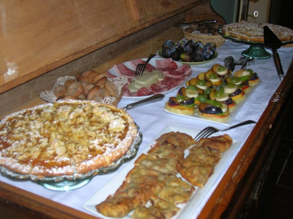 A cozy indoor buffet table laden with an array of delectable pastries, fruits, meats, and cheeses, inviting travelers to indulge in a warm and rustic dining experience.