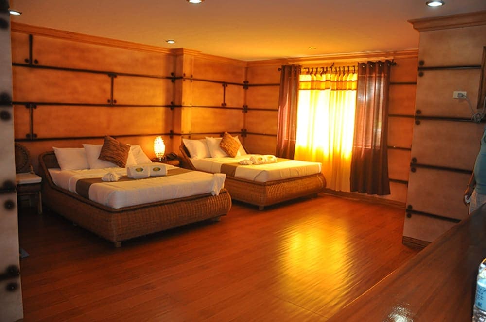 A cozy hotel room with warm wooden walls, two neatly arranged beds, and golden curtains bathed in soft light, ideal for travelers seeking comfort and relaxation.