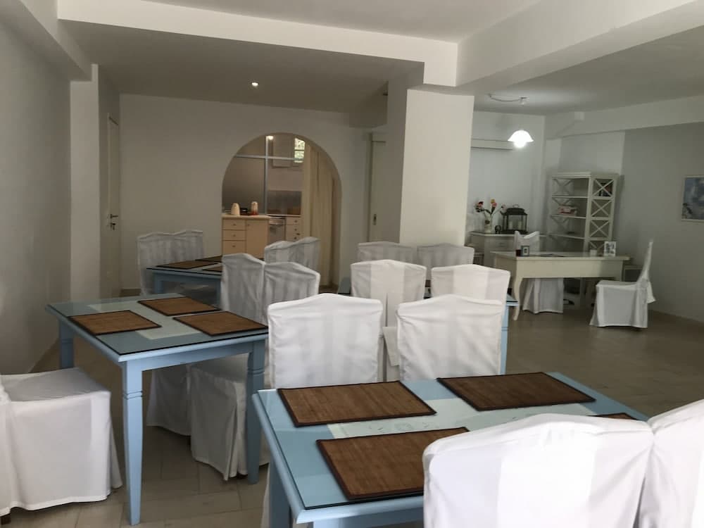 A cozy indoor dining area with white-covered chairs, light blue tables, and wooden placemats creates a serene atmosphere ideal for family gatherings or intimate dinners.