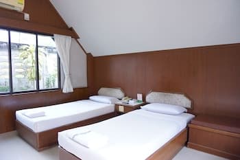 A cozy attic-style bedroom with two neatly made beds, wooden furnishings, and a window view of greenery, ideal for a serene getaway or family accommodation.