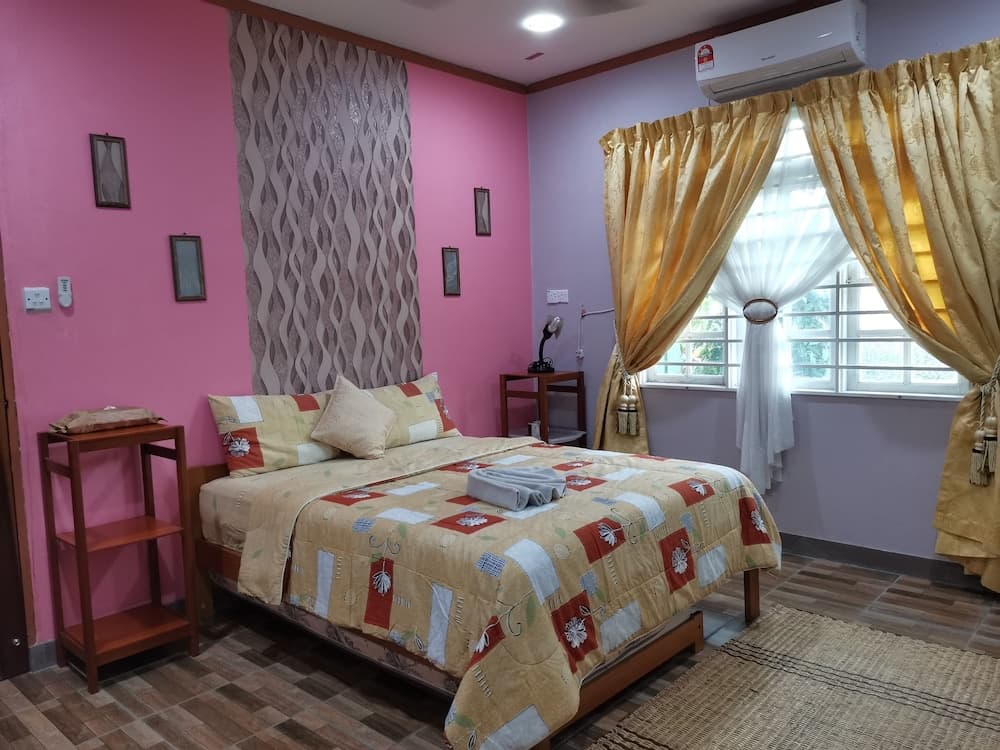 A cozy bedroom with pink walls, a patterned quilt on the bed, golden curtains, and natural light streaming through the window, ideal for travelers seeking a comfortable and inviting accommodation.