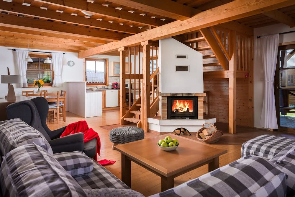 A cozy cabin interior featuring a warm fireplace, wooden beams, and comfortable seating creates an inviting atmosphere perfect for a relaxing getaway.