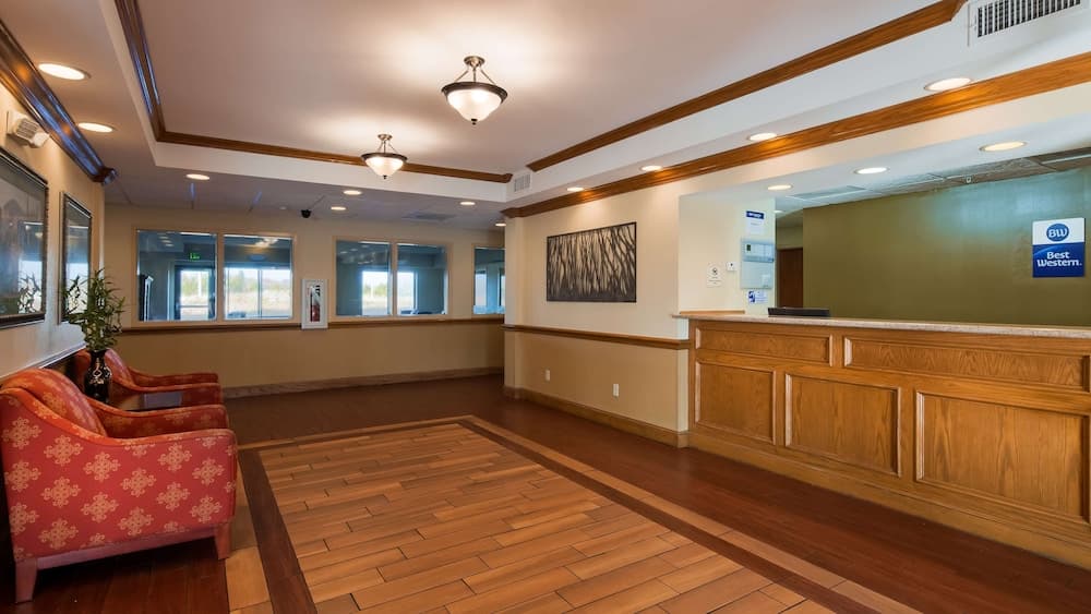 A cozy hotel lobby features warm wooden floors, inviting armchairs, and a reception desk under soft lighting, ideal for travelers seeking comfort and convenience.