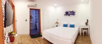 A cozy, modern bedroom with white furnishings, wooden flooring, and vibrant blue pillows creates a serene atmosphere, ideal for travelers seeking a comfortable and stylish accommodation.