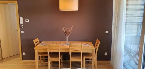 A cozy dining area with wooden furniture and a vase of dried flowers set against a warm-toned wall, ideal for travelers seeking a comfortable and inviting accommodation space.
