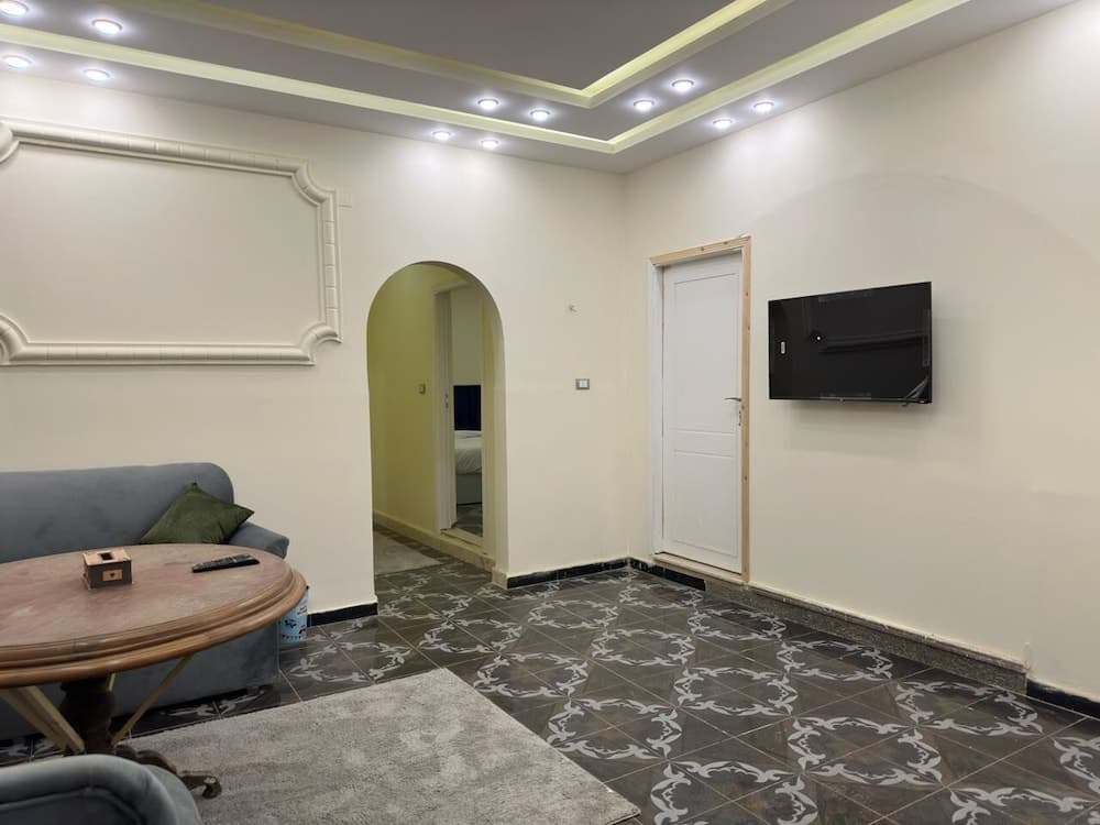 A cozy living room with patterned tiles, a plush sofa, a wooden coffee table, and a mounted TV creates a welcoming atmosphere ideal for travelers seeking comfort in a home-like setting.