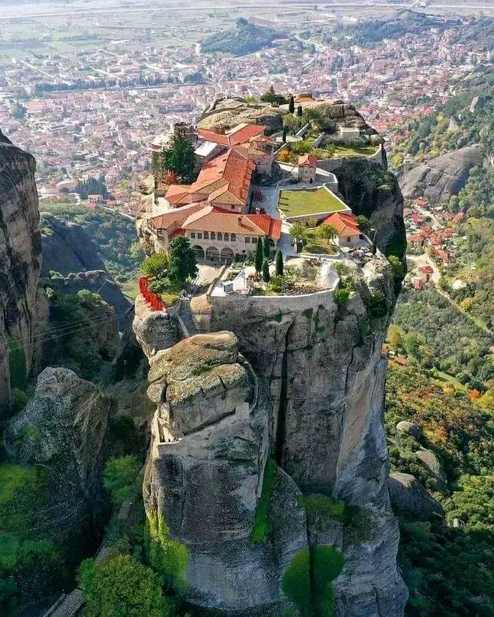 A breathtaking aerial view captures the serene monasteries perched atop towering rock formations overlooking the lush valley of Kalabaka, Greece, ideal for spiritual retreats and adventure seekers exploring unique geological wonders.