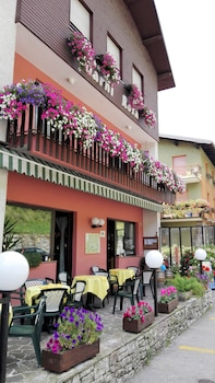 A charming European café with vibrant flower-decked balconies invites travelers to relax in its cozy outdoor seating area, perfect for a leisurely coffee break amidst picturesque surroundings.