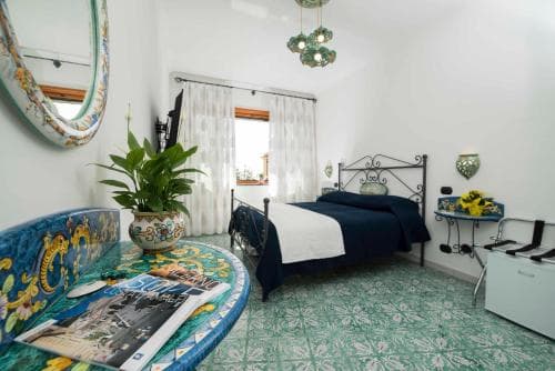 A cozy bedroom with vibrant green tiled floors, ornate mosaic furniture, and a neatly made bed exudes a charming, artistic ambiance perfect for travelers seeking a unique and culturally rich accommodation experience.