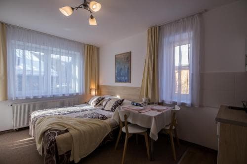 A cozy hotel room with soft lighting, a neatly made bed, a small dining table by the window, and warm curtains creates an inviting atmosphere perfect for travelers seeking comfort and relaxation.