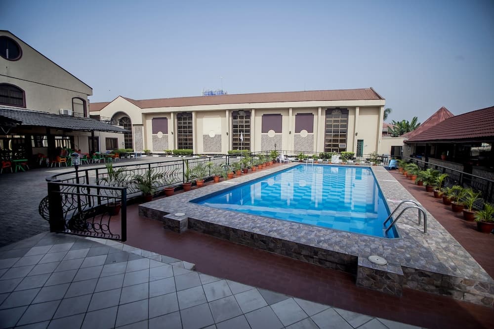 A serene outdoor pool area surrounded by potted plants and modern architecture offers a relaxing retreat for travelers seeking leisure and comfort.