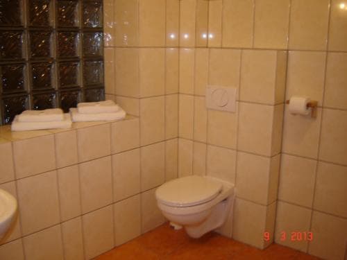 A cozy hotel bathroom features beige tiled walls, a toilet, neatly folded towels on a ledge, and a glass block window, ideal for travelers seeking comfort and cleanliness.