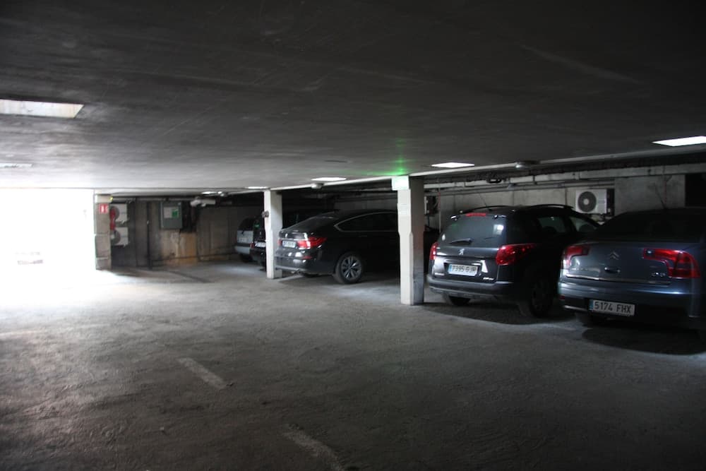 A dimly lit underground parking garage with parked cars creates a quiet urban atmosphere, ideal for travelers seeking secure vehicle storage during city exploration.