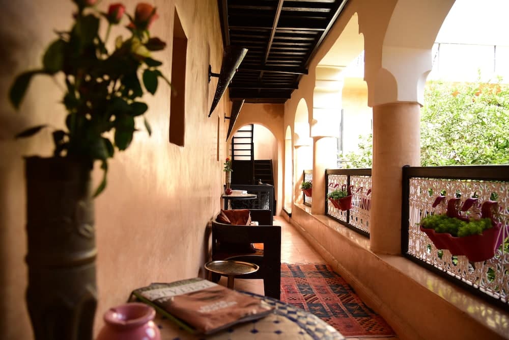 A serene Mediterranean-style balcony features arched columns, vibrant potted plants, and cozy seating, ideal for travelers seeking a tranquil retreat in a historic villa.
