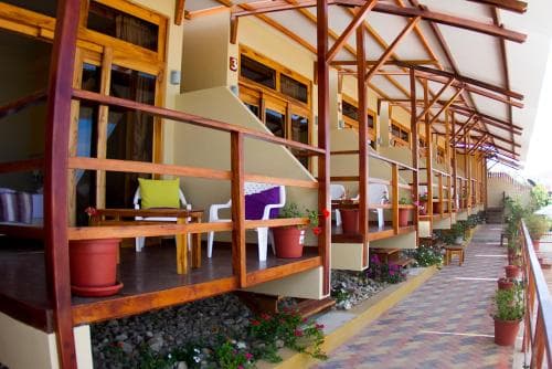 A cozy hotel corridor lined with wooden balconies adorned with potted plants and comfortable seating, evoking a warm and inviting atmosphere ideal for travelers seeking relaxation.