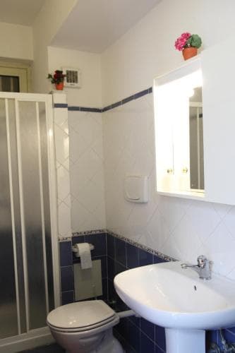 A cozy bathroom with white tiles, blue accents, and floral decorations offers a clean and inviting space for travelers seeking comfort during their stay.