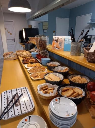 A cozy breakfast buffet area with an inviting spread of pastries, breads, and condiments on a warm yellow countertop, perfect for travelers seeking a comfortable morning meal in a welcoming indoor setting.
