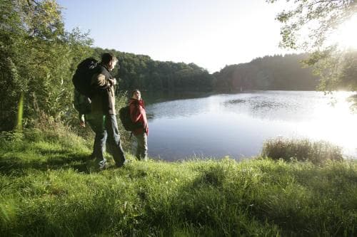 Two hikers pause by a serene lakeside surrounded by lush greenery, capturing the tranquil mood of a peaceful outdoor adventure ideal for nature lovers seeking relaxation.