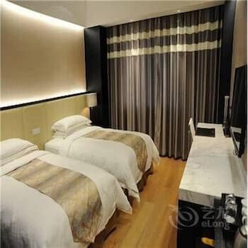 A cozy hotel room with two neatly made beds, warm lighting, and elegant curtains creates a serene atmosphere, ideal for travelers seeking comfort and relaxation during their stay.