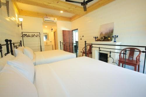 A cozy hotel room with two neatly made beds, rustic wooden ceilings, and warm lighting creates an inviting atmosphere, perfect for travelers seeking comfort and relaxation.