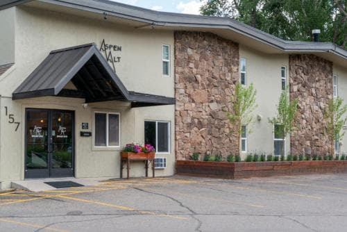 A cozy motel entrance with stone accents and a welcoming flower box invites travelers to unwind in a serene suburban setting.