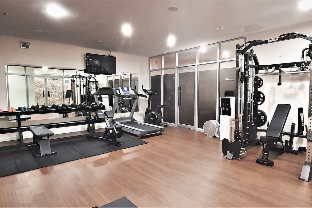 A well-lit indoor fitness center features modern equipment like treadmills, weight machines, and free weights, creating an inviting atmosphere for travelers seeking a workout-friendly accommodation option.