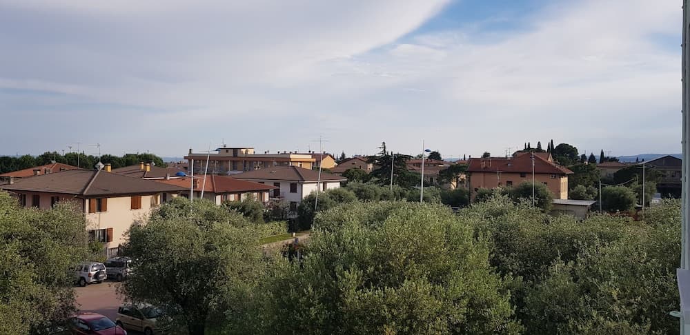 A serene suburban landscape featuring terracotta-roofed houses nestled among lush greenery under a partly cloudy sky, ideal for travelers seeking a peaceful residential retreat.
