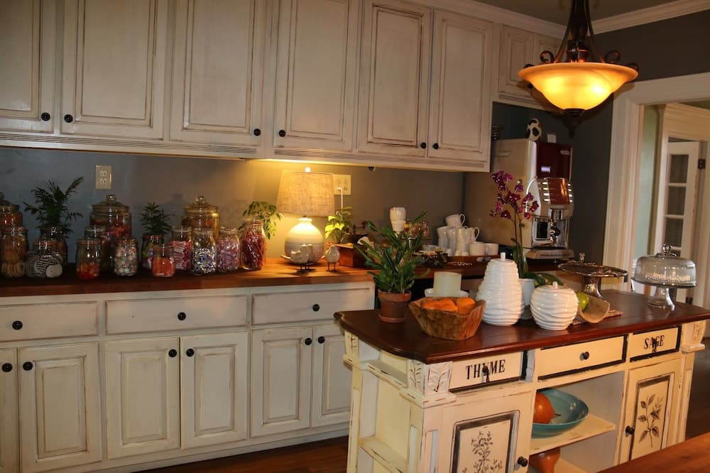 A cozy kitchen with white cabinets, a warm pendant light, and a wooden island adorned with plants, jars of candy, and decorative items, perfect for a homey culinary retreat or interior design inspiration.