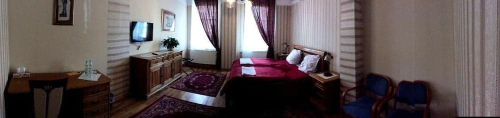 A cozy hotel room features a neatly made bed, wooden furniture, vibrant rugs, and soft lighting, creating a warm and inviting atmosphere ideal for travelers seeking comfort and relaxation.