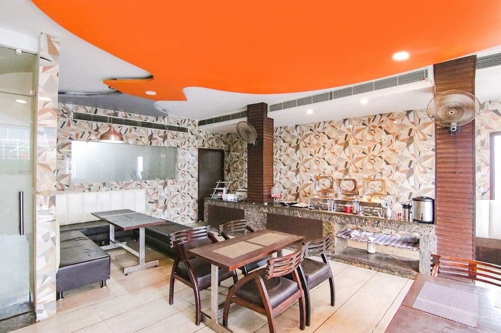 A vibrant dining area with an orange ceiling, geometric-patterned walls, and modern furniture creates a cozy atmosphere ideal for travelers seeking a stylish yet comfortable restaurant experience.
