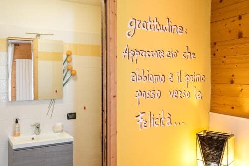 A cozy bathroom with wooden walls and a motivational quote on a yellow wall creates a warm, uplifting atmosphere, ideal for travelers seeking relaxation and inspiration during their stay.